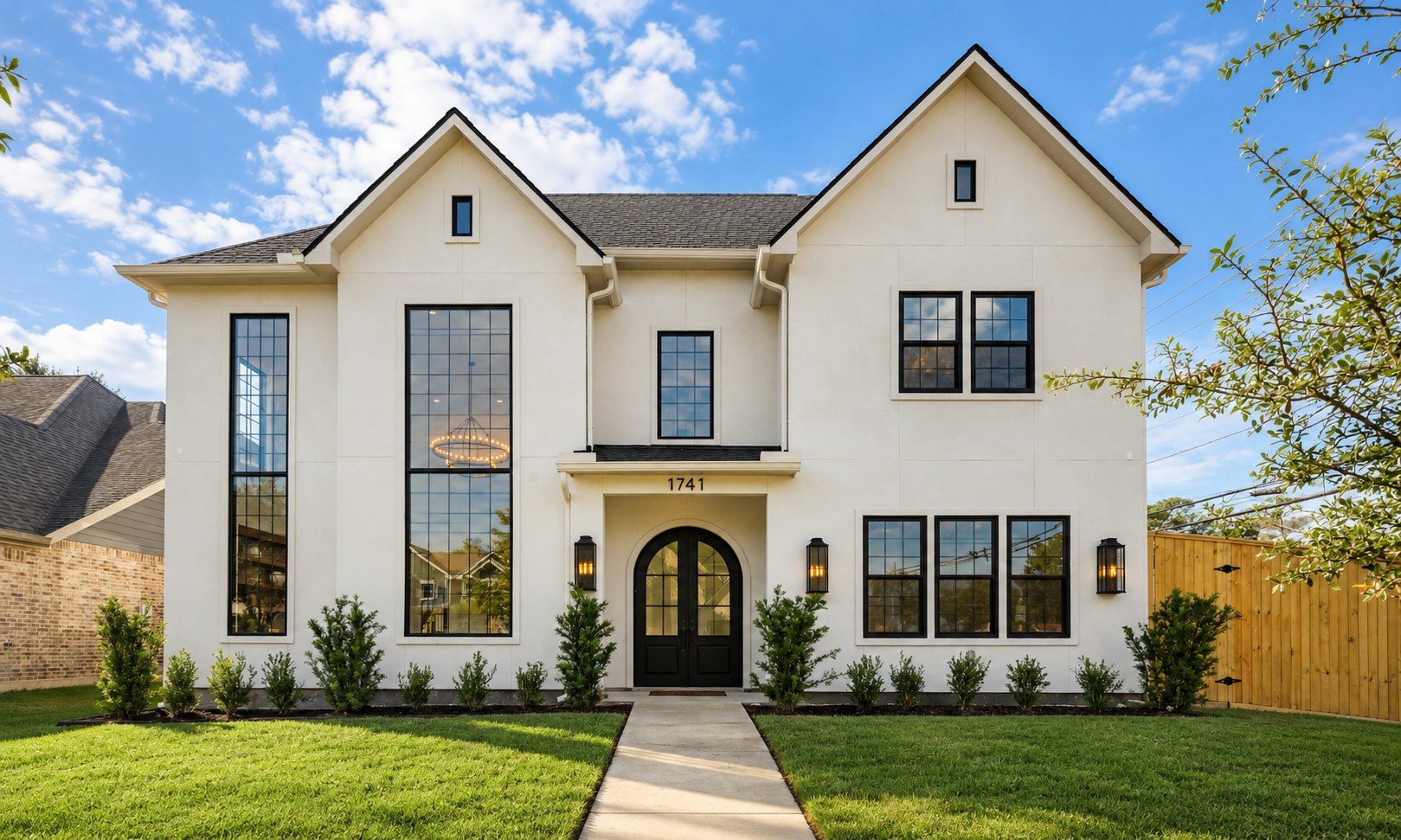 R+R Garden Oaks: finished white stucco facade with arched black front doors and tall grid windows